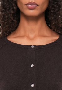 Cardigã de malha castanho com um decote redondo, fecho de cinco botões com botões de cor clara e uma textura suave e macia.