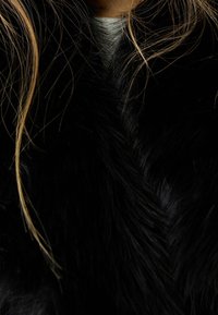 Black faux fur scarf with a soft, textured surface. Features a diagonal chevron pattern and fine, shiny strands.