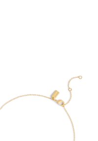 Bracelet en chaîne dorée avec une surface texturée, doté d'un fermoir et d'une longueur ajustable, souligné par une petite étiquette avec un logo gravé.