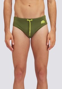 Grüne Schwimmhose mit glatter Textur, ausgestattet mit einem gelben Kordelzug und einem Logo-Element auf der Vorderseite. Klassisches Badebekleidungsdesign.
