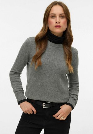 Pelēks adīts džemperis ar augstu melnu augstu apkakli, garām piedurknēm, pieguļošu dizainu un ribotu aproci, saskaņots ar melnām biksēm un sudrabota sprādzes jostu.