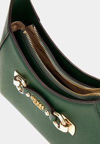 Bolso de mano texturizado verde con herrajes dorados, que cuenta con múltiples compartimentos con cremallera y un acento de logo. El diseño es estructurado con un acabado suave.