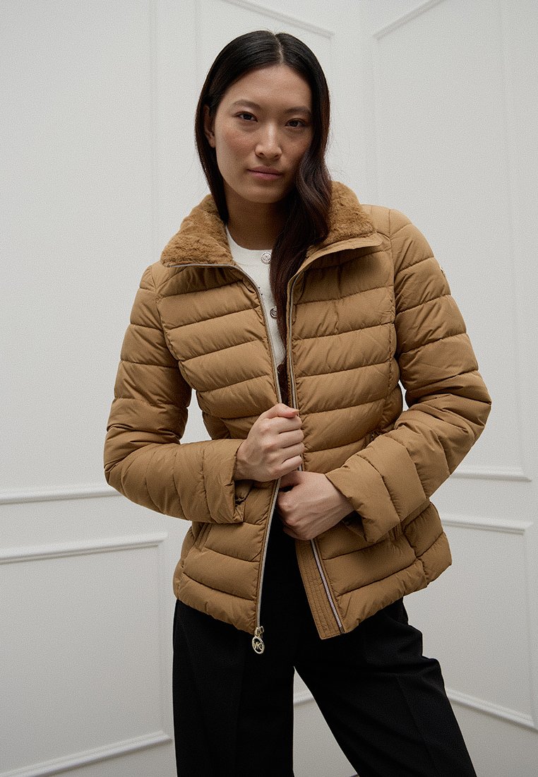 Braune gepolsterte Jacke mit Kragen aus Kunstfell und Reißverschluss. Verfügt über horizontale Steppung und Seitentaschen, geeignet für kaltes Wetter.