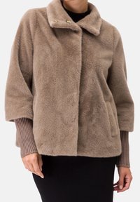 Chaqueta de piel sintética color canela con cuello, cierre de dos botones y mangas tres cuartos, con puños de punto acanalado y bolsillos laterales.