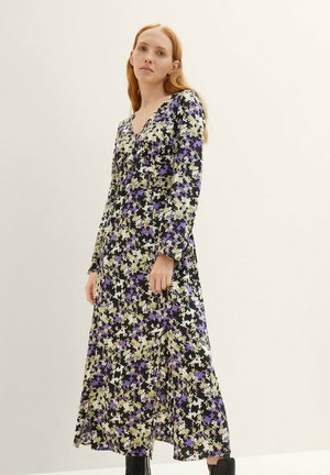 Schwarzes langärmeliges Kleid mit einem floralen Muster in Lila und Gelb. V-Ausschnitt und ein fließendes Design, mit einem Schlitz am Saum.