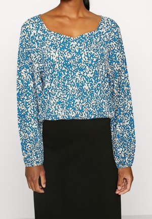 Bluse mit blau-weißem Muster, langen Ärmeln und V-Ausschnitt. Baumwollstoff mit lockerer Passform, die kurz über der Taille endet.