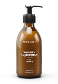 Bernsteinfarbene Glasflasche mit einer schwarzen Pumpspule. Das Etikett zeigt weißen Text mit der Aufschrift "Volumen Conditioner" und Inhaltsstoffen, entwickelt für feines Haar.