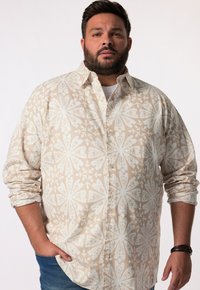 Camicia button-up beige chiaro con motivo floreale bianco, maniche lunghe arrotolate e taschino sul petto. Tessuto di cotone testurizzato. Design casual.
