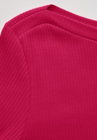 Fuchsiefarbener gerippter Stoff mit strukturiertem Ausschnitt und glatter Textur; verfügt über eine diagonale Nahtdetails an der Schulter.