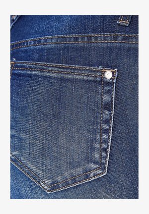 Denim jeans met een close-up van de achterzak. Kenmerkt zich door de donkerblauwe kleur, dubbele stiksels en een metalen knoopdetail.