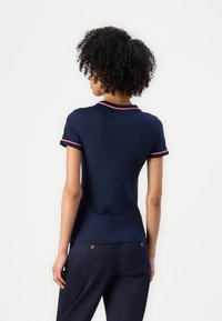 Navy polo skjorte med kortermede og røde detaljer på kragen og mansjettene. Figurtilpasset design, laget av glatt stoff, minimalistisk stil.