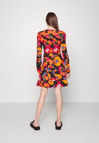 Vestido floral de mangas longas em preto, com flores vibrantes em laranja, rosa e verde, um corpete ajustado e uma barra flared.