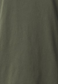 Tissu en coton vert olive avec une texture douce et une finition lisse. Aucun motif ou design visible. Idéal pour les vêtements décontractés.