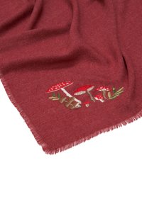 Écharpe rouge en tissu doux, ornée de détails brodés de champignons rouges et de feuillage vert près du bord, avec des bords effilochés.