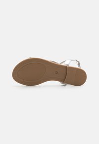 Silver sandal with adjustable strap, rubber sole, textured grip pattern, and a flat heel. Predominantly metallic finish and neutral color.