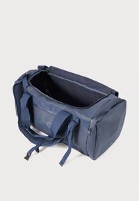 Bolso de deporte de tela duradera en color navy, con asas dobles en la parte superior, un compartimento con cremallera y detalles de malla para añadir textura.