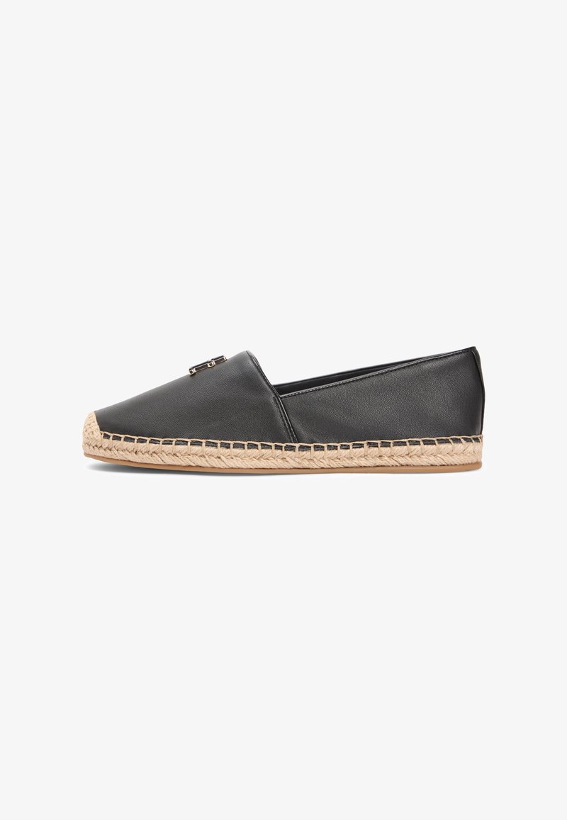 Espadrilles plates en cuir noir avec une semelle en jute tressé, un bout pointu et un accent métallique sur le dessus.