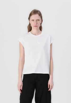 T-shirt bianco in cotone con maniche a cappuccio, scollo rotondo e un dettaglio logo discreto. Completato da pantaloni neri per creare contrasto.