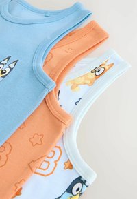 Drie katoenen tanktops: één lichtblauw met een afbeelding, één oranje met een sterrenpatroon, en één lichtblauw met tekenfilmfiguren.