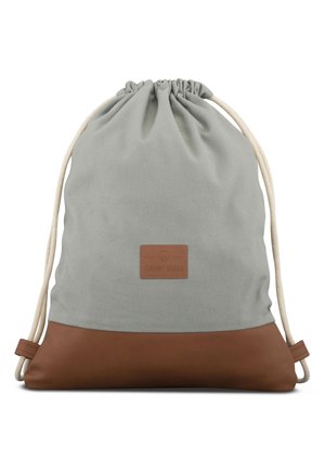 Mochila gris con cordón, base de cuero marrón y un pequeño parche rectangular en la parte frontal, con cordones de color crema.