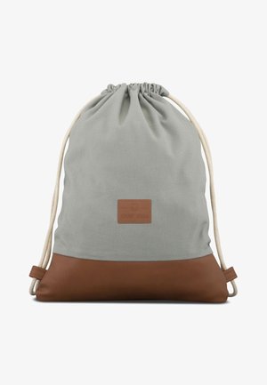 Mochila gris con cordón, base de cuero marrón y un pequeño parche rectangular en la parte frontal, con cordones de color crema.