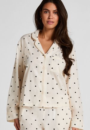 Roomkleurige pyjama set met een bovenstuk met knopen, zwarte polka dots, lange mouwen, een borstzak en bijpassende broek.