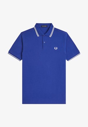 Polo de manga corta azul con doble raya blanca en el cuello y las mangas, tapeta con dos botones y pequeño logo blanco de laurel en el pecho.