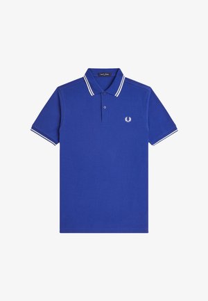 Polo de manga corta azul con doble raya blanca en el cuello y las mangas, tapeta con dos botones y pequeño logo blanco de laurel en el pecho.