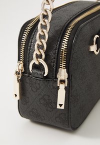 Borsa nera in pelle sintetica texturizzata con hardware dorato, doppi zip e una catena spessa come tracolla. Presenta un motivo distintivo e accenti.