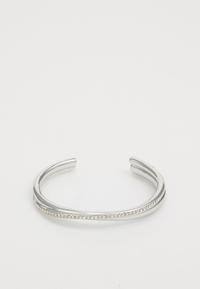 Silvrig armbandsmanchett med en slät yta och en rad klara stenar på ena sidan, vilket ger en subtil accent.