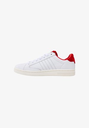 White sneaker with red accents, smooth leather material, rounded toe, flat laces, and perforated detailing on the side.