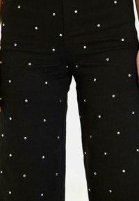 Pantaloni neri in twill di cotone, decorati con brillanti argento sparsi sulla stoffa, con un design a gamba dritta.