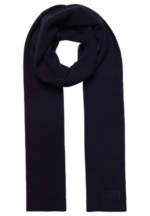 Ciemnogranatowy dziany szalik złożony z małą prostokątną metką przyszytą blisko jednego końca.