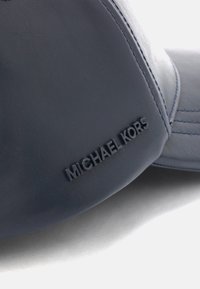 Casquette en cuir marine au toucher lisse, ornée du logo "MICHAEL KORS" en relief sur le côté et de coutures contrastées le long des coutures.