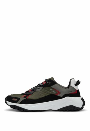 Sneaker nero e oliva con tomaia strutturata, dettagli rossi e intersuola bianca. Presenta lacci a contrasto e suola robusta.