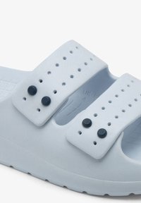 Light blue rubber sandals with two adjustable straps featuring black buttons and ventilation holes, textured inside, and a thick sole.