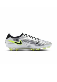 La scarpa da calcio argento presenta una superficie testurizzata con accenti neri, un logo Nike verde neon e tacchetti sagomati per una maggiore trazione.