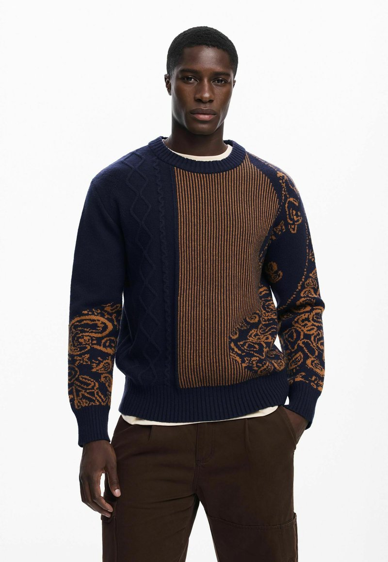Navy and brown knitted sweater featuring cable and striped patterns with floral accents. Ribbed cuffs and hem; round neckline.