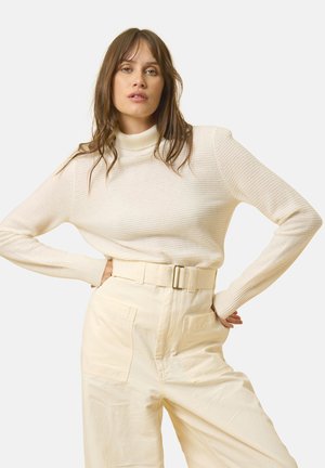 Cream ribbed turtleneck sweater paired with high-waisted beige wide-leg trousers featuring a belt and large pockets. Smooth texture.