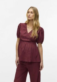 Top bordeaux texturizzato con design avvolgente e maniche corte a sbuffo, abbinato a pantaloni a vestibilità morbida dello stesso colore, su uno sfondo neutro.