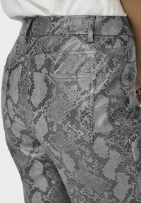 Pantaloni grigi a stampa serpente con una finitura strutturata, dotati di vita aderente, due tasche posteriori e un'area decorativa per la cintura.