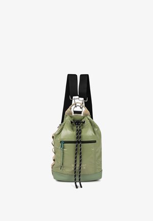 Mochila verde con cordón, con correas negras ajustables, bolsillo delantero con cremallera y asa superior color cuero claro.