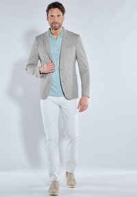 Gray textured blazer over a light blue polo, paired with white trousers and beige slip-on shoes. Simple, tailored design without patterns.
