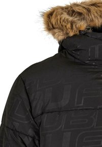 Giacca puffa nera con cappuccio foderato in pelliccia sintetica, sezioni cucite e un delicato motivo logo tonale sul tessuto.