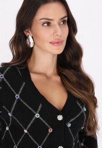 Cardigan nero con motivo a diamante e decorazioni in gemme multicolori, scollatura a V profonda e maniche lunghe. Tessuto a maglia testurizzato.