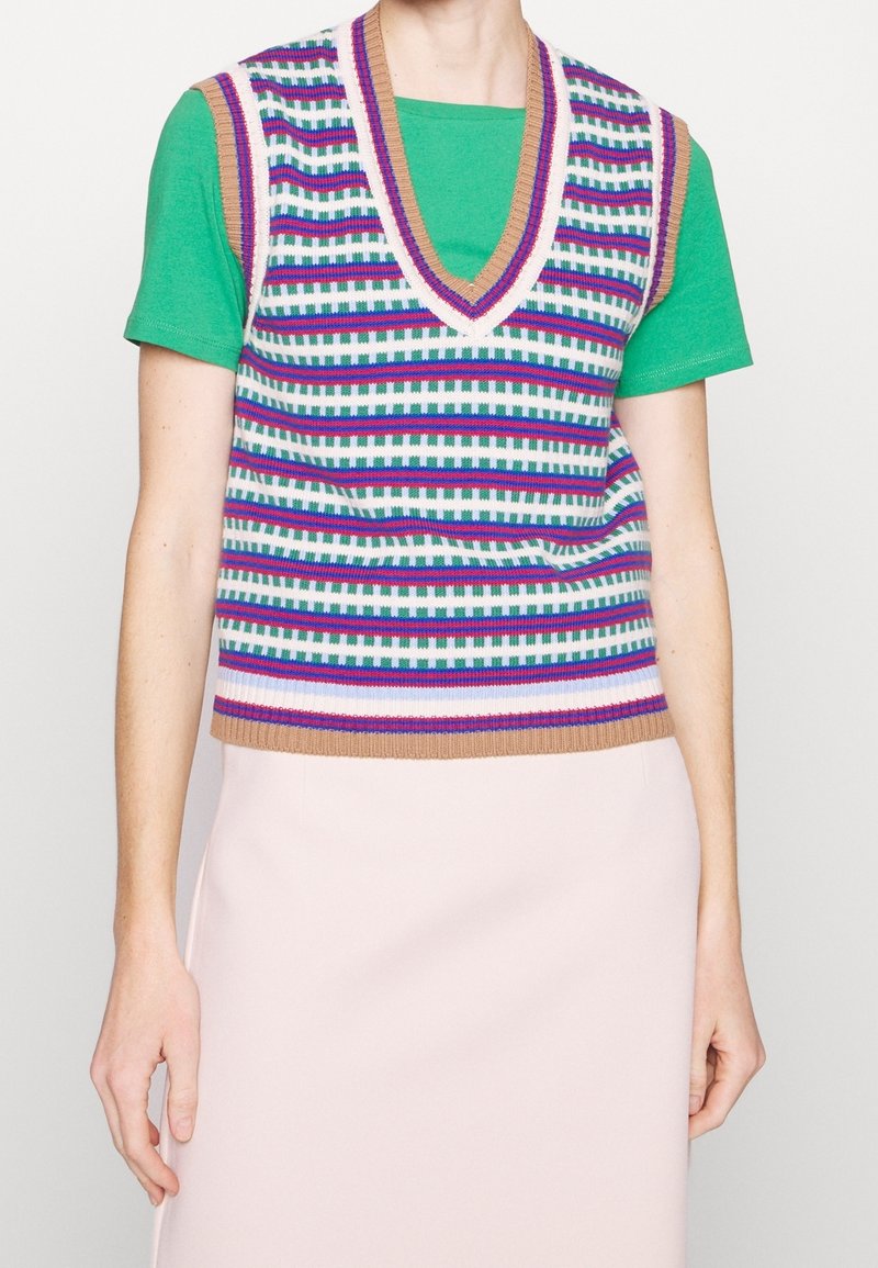 Gilet sans manches en tricot avec des rayures horizontales multicolores, doté d'un encolure en V et d'un ourlet côtelé, porté par-dessus un T-shirt vert.