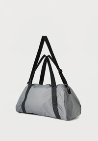 Šedá sportovní taška z odolné látky s černými popruhy, zaobleným tvarem, zapínáním na zip a zesílenými švy pro zvýšenou pevnost.