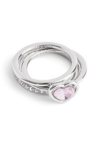 Three silver rings stacked together, featuring a heart-shaped pink gemstone and a row of small gemstones along one band.