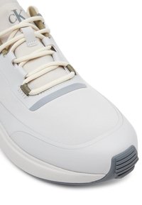 Sneaker Calvin Klein con una toma superiore leggera di colore bianco, tessuto testurizzato, accenti grigi e suola in gomma con dettagli rigati.