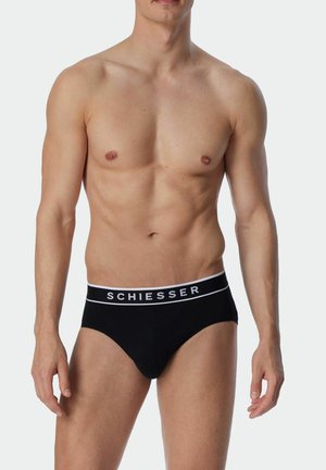 Black cotton brief with a white elastic waistband, featuring the brand name "SCHIESSER" in black lettering. Simple, classic design.